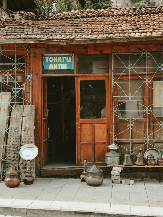 a store with pots and pans in front of it, a picture, trending on unsplash, art nouveau, turkey, standing in township street, wooden banks, located in hajibektash complex