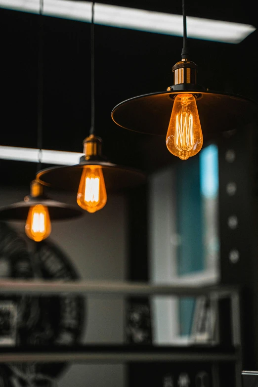 a bunch of light bulbs hanging from a ceiling, pexels contest winner, light and space, cafe lighting, orange teal lighting, with a black dark background, sconces