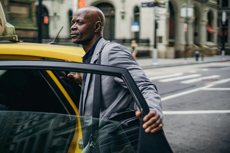 a man in a suit getting out of a taxi, a photo, by Daniel Gelon, pexels contest winner, renaissance, portrait of samuel l. jackson, bald man, yellow and charcoal, humans of new york style