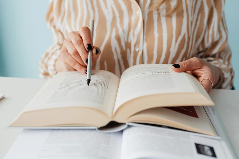 a woman sitting at a table with an open book and a pen, informative texts, perfectly detailed, thumbnail, holding books