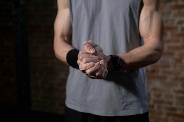 a man standing in front of a brick wall holding his hands together, trending on pexels, local gym, partially cupping her hands, crossed arms, clint clearley