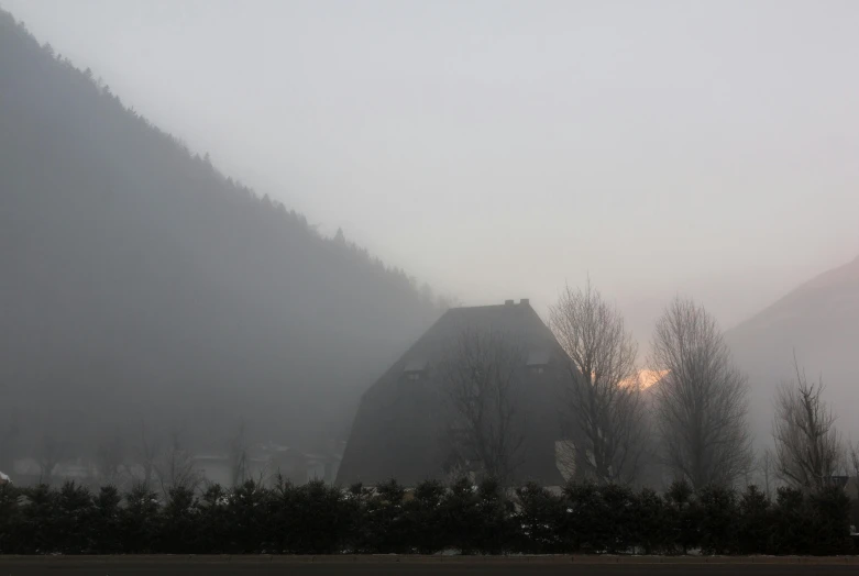 a barn surrounded by trees on a foggy day, a picture, by Jan Tengnagel, pexels contest winner, baroque, cold sunset, mountain, view from the street, taken in the late 2010s