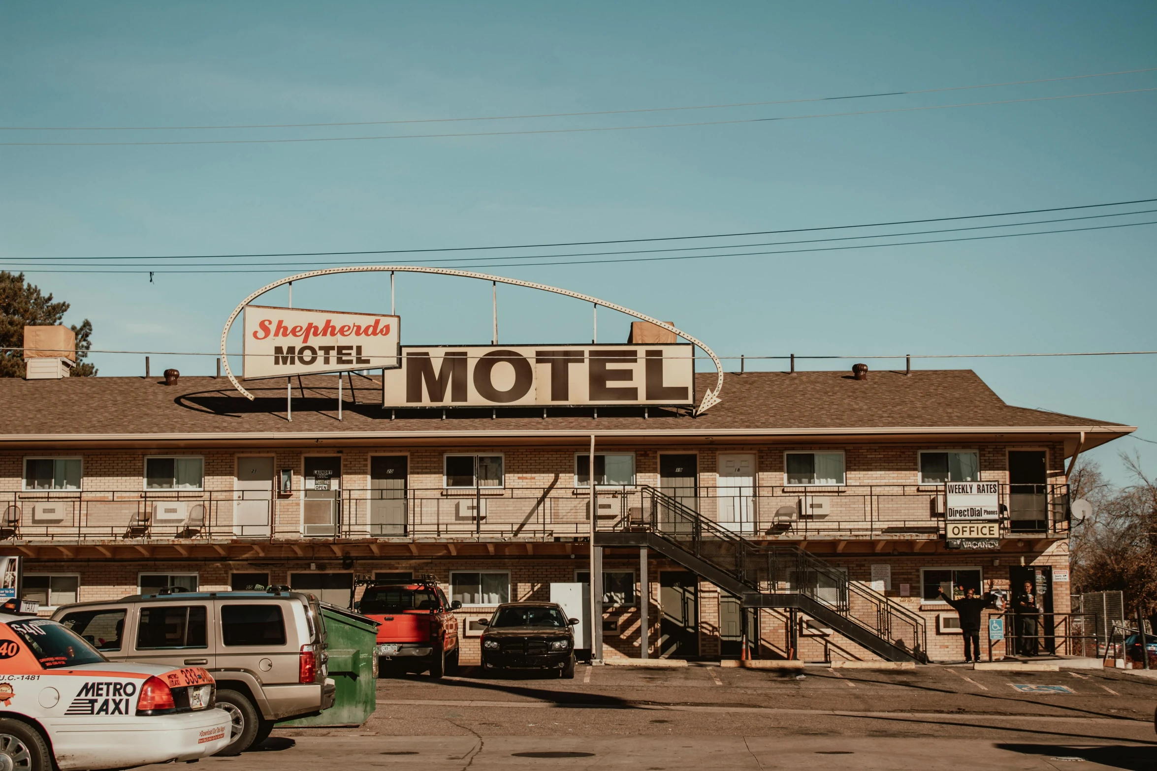a motel with cars parked in front of it, unsplash, sheild, drumheller, brown, exterior
