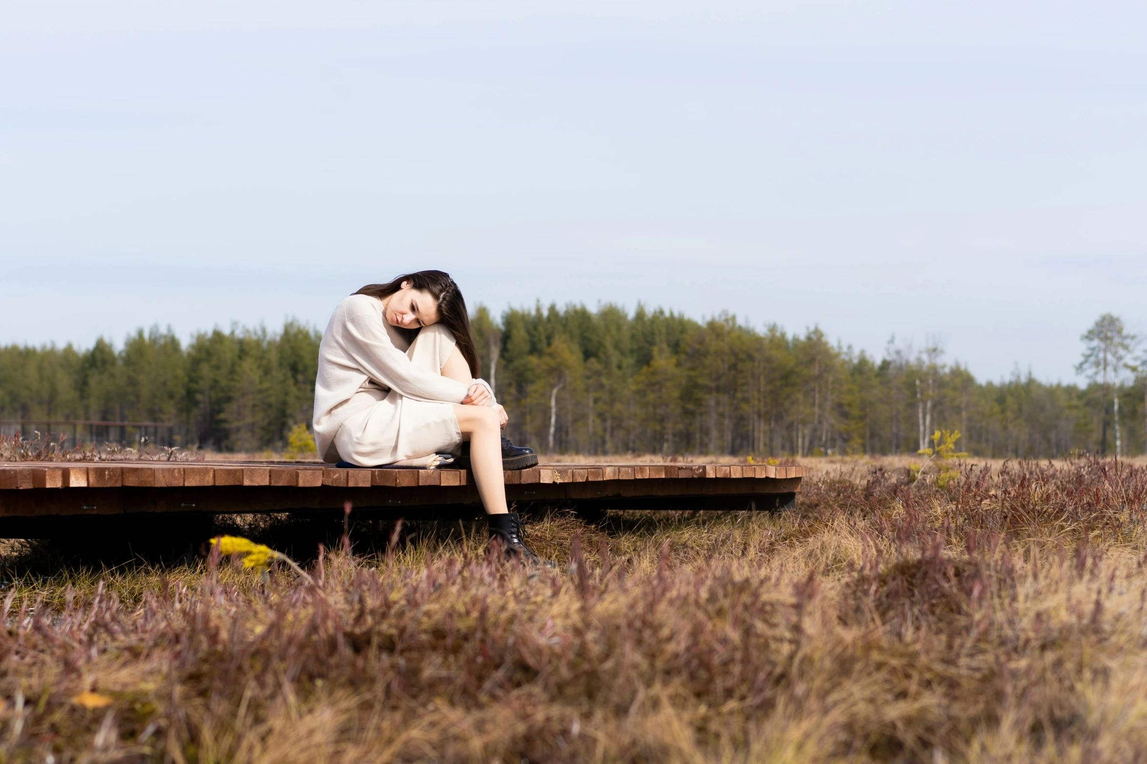 a woman sitting on a wooden platform in a field, a portrait, by Jaakko Mattila, unsplash, woman very tired, sitting on a mocha-colored table, in a swamp, concept photoset