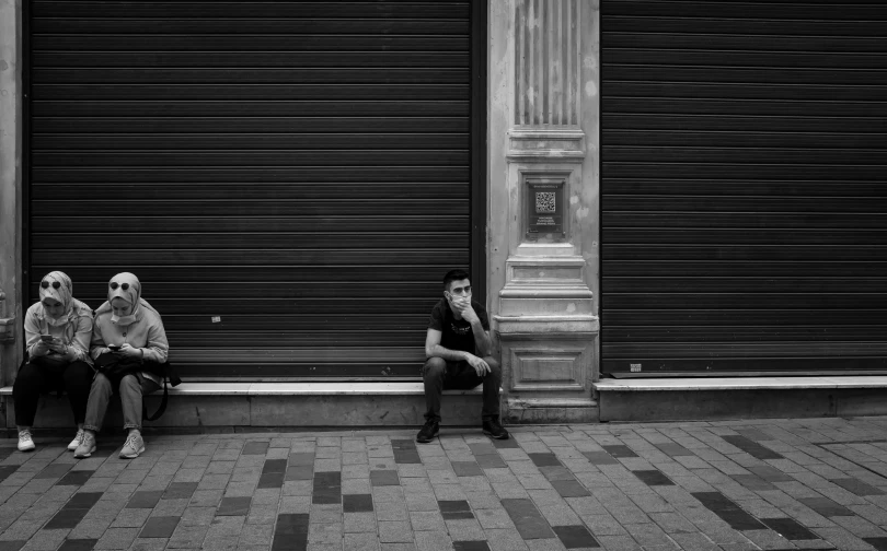 a couple of men sitting next to each other on a sidewalk, a black and white photo, by Michalis Oikonomou, pexels contest winner, stood outside a corner shop, young man with short, azamat khairov, hes alone