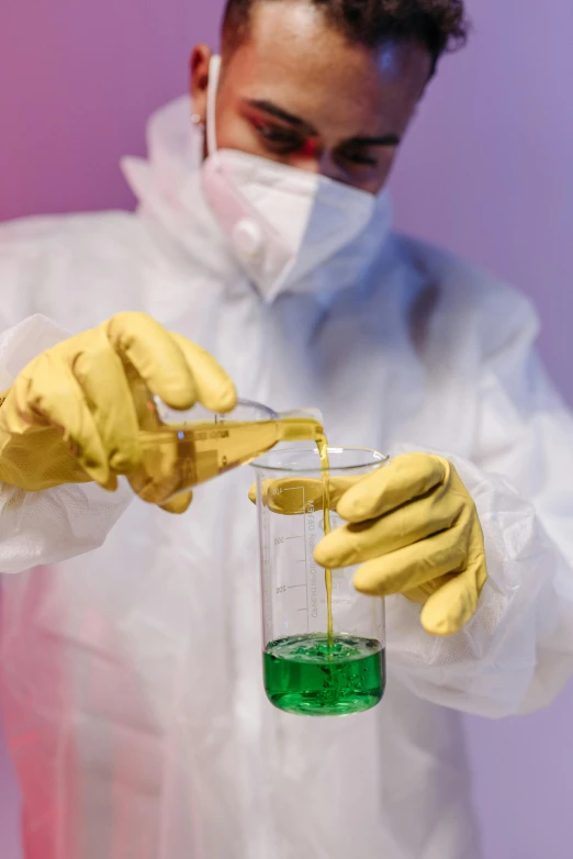 a man in a lab coat pouring liquid into a beakle, by Adam Marczyński, shutterstock, yellow latex gloves, a green, gold, flight suit and gloves