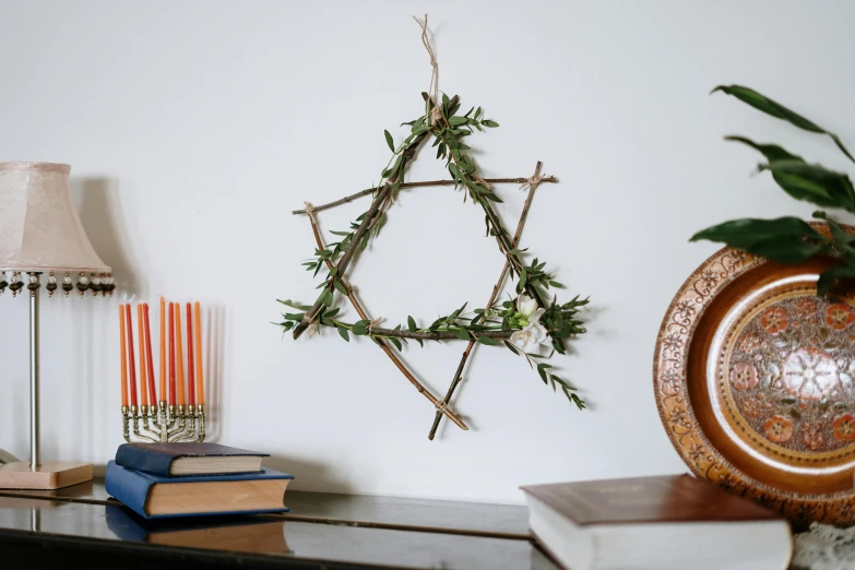 a wooden star of david hanging on a wall, inspired by Andy Goldsworthy, folk art, willowy frame, herbs, festive, press shot