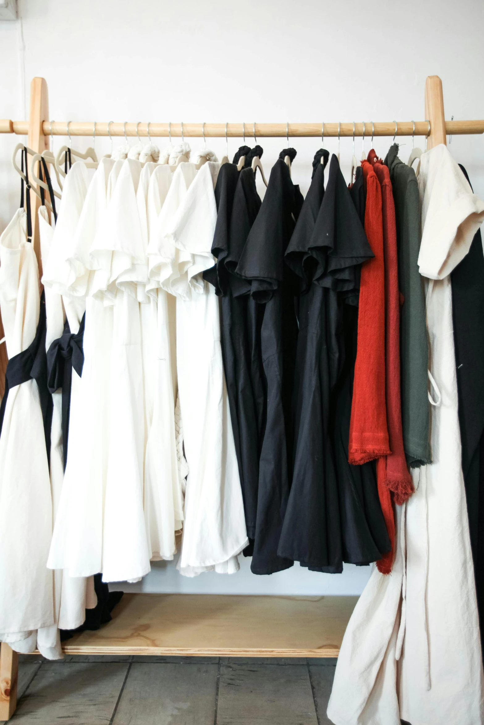 clothes hanging on a rack in a clothing store, by Gen Paul, unsplash, renaissance, yohji yamamoto, nico wearing a white dress, red and white and black colors, flat lay