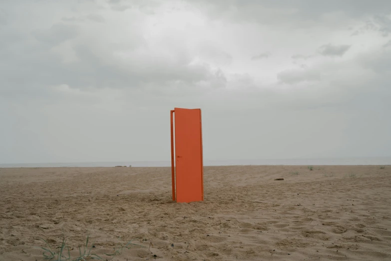 an orange door sitting on top of a sandy beach, by Attila Meszlenyi, conceptual art, slight overcast lighting, ignant, lena oxton, with a square