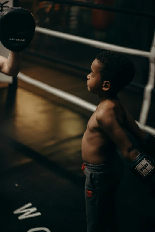 a young boy standing next to a boxing ring, pexels contest winner, happening, lifting weights, african american, with a kid, 6 pack ab