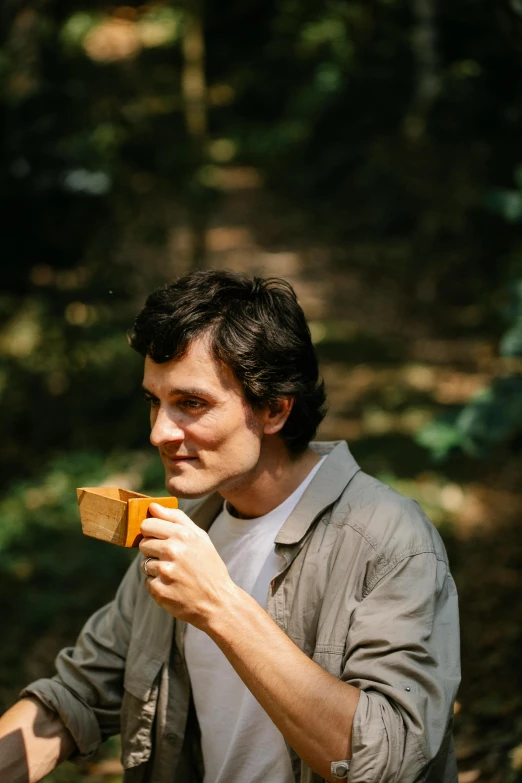 a man holding a piece of wood in his hand, an album cover, by Sven Erixson, unsplash, having a picnic, profile portrait, will graham, cast
