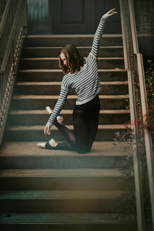 a woman sitting on top of a set of stairs, unsplash contest winner, arabesque, striped sweater, tendu pose, girl graceful, carson ellis