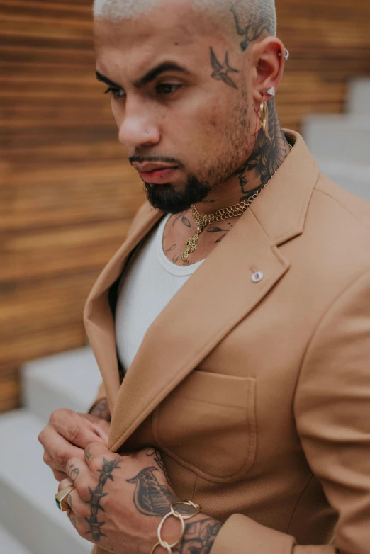 a man wearing a tan suit and a white t - shirt, an album cover, inspired by Byron Galvez, trending on pexels, wearing detailed leather collar, rapper bling jewelry, tattooed man, high details!