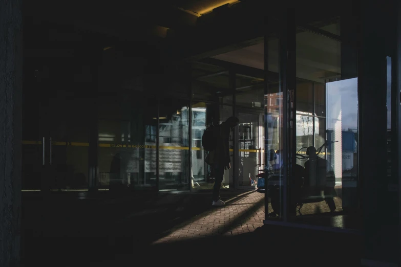 a group of people standing outside of a building, by Jan Tengnagel, pexels contest winner, dark city bus stop, reflections. shady, terminal, studying in a brightly lit room