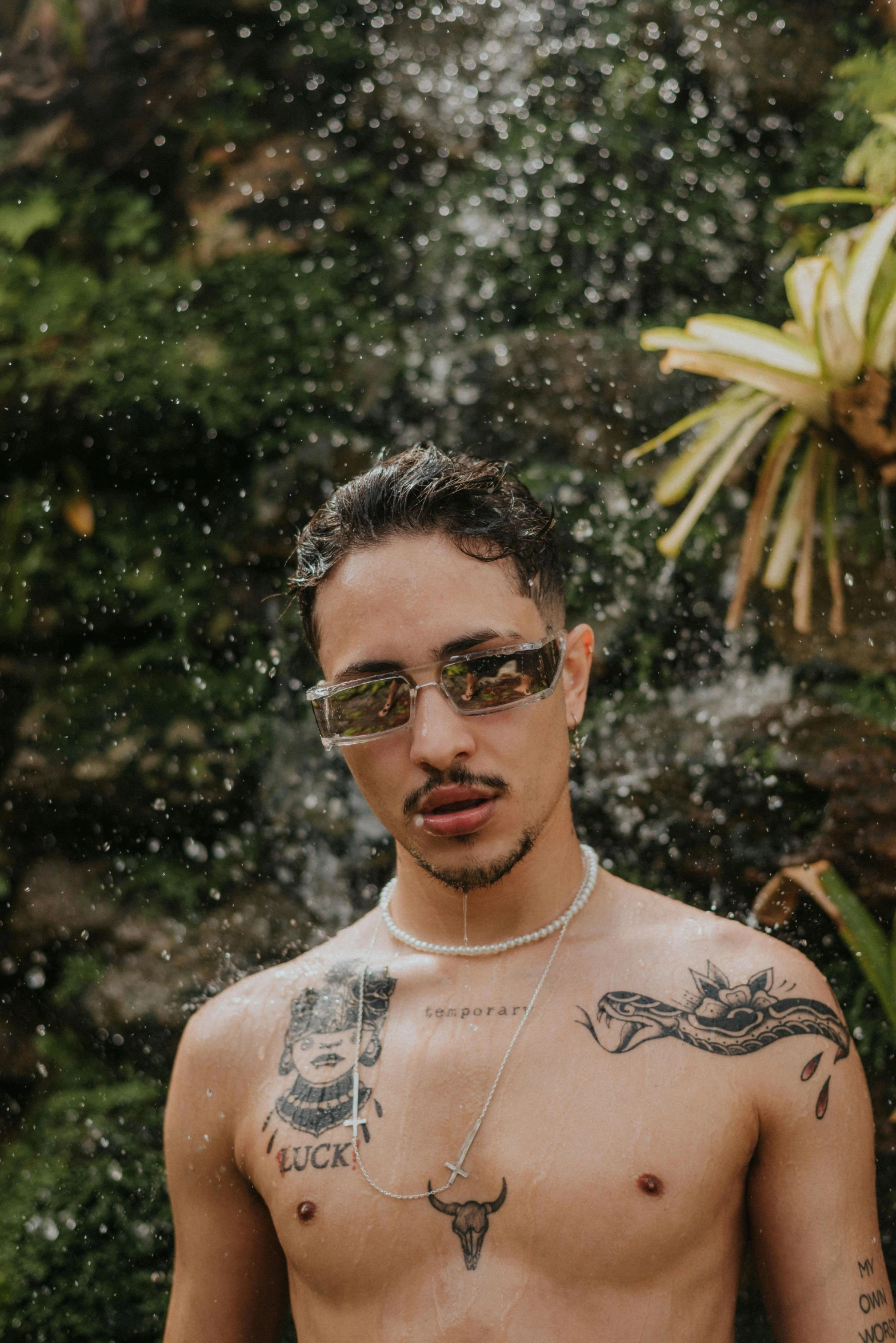 a shirtless man standing in front of a waterfall, an album cover, inspired by Byron Galvez, trending on pexels, he wears an eyepatch, androgynous person, anaconda, snapchat photo