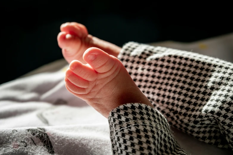 a close up of a baby's foot on a bed, unsplash, getty images, extra high resolution, on a checkered floor, the birth