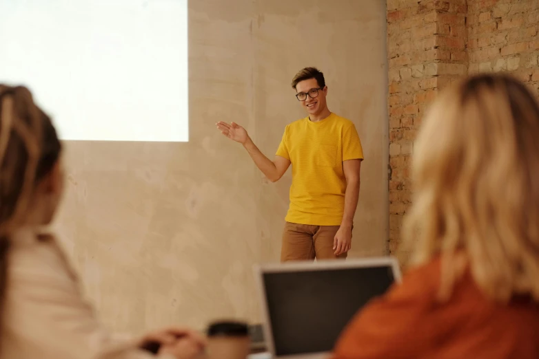 a man giving a presentation to a group of people, by Adam Marczyński, pexels, wearing a modern yellow tshirt, avatar image, mid shot photo, background image