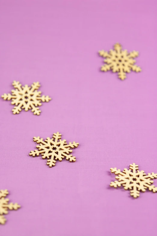 gold snowflakes on a purple background, trending on pexels, process art, wooden decoration, mini model, scattered props, pink and gold