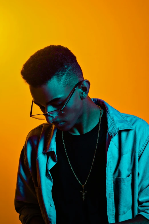 a man standing in front of a yellow background, an album cover, inspired by Xanthus Russell Smith, trending on pexels, posing in dramatic lighting, profile posing, androgynous male, man with glasses