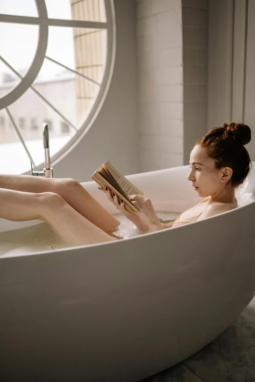 a woman sitting in a bathtub reading a book, by Julia Pishtar, pexels contest winner, curved body, skincare, float, pale skin