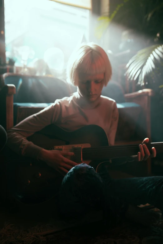 a woman sitting on the floor playing a guitar, an album cover, inspired by Elsa Bleda, pexels contest winner, short platinum hair tomboy, cinematic atmospheric photo, sitting in a lounge, young blonde boy fantasy thief