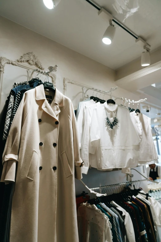 a rack of clothes in a clothing store, trending on pexels, renaissance, wearing a white winter coat, wearing a trenchcoat, tiffany style, cream - colored room