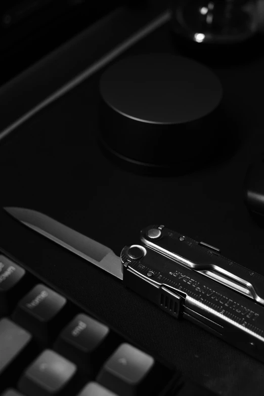 a pocket knife sitting on top of a keyboard, a black and white photo, by Adam Marczyński, hasselblad, (sfw) safe for work, tactical, beaten tech. neo noir style