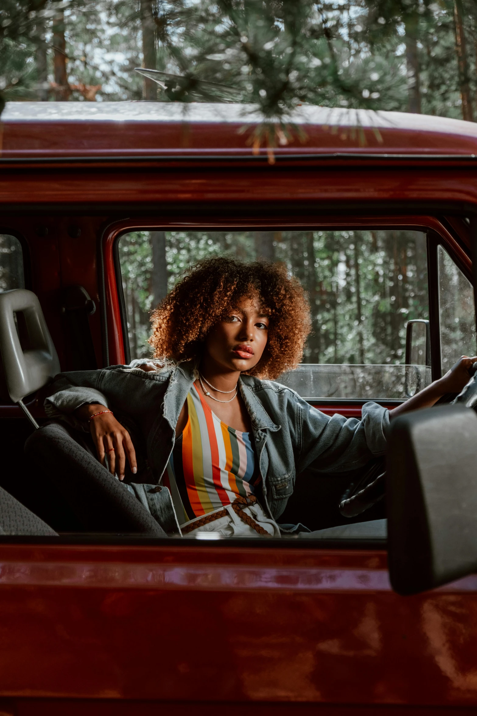 a woman sitting in the driver's seat of a red truck, pexels contest winner, renaissance, curly afro, muted colors. ue 5, casually dressed, handsome girl