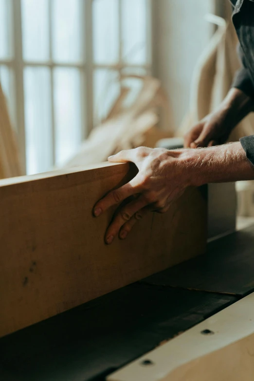 a man working on a piece of wood, by Jessie Algie, trending on unsplash, rectangle, furniture, back facing, hand
