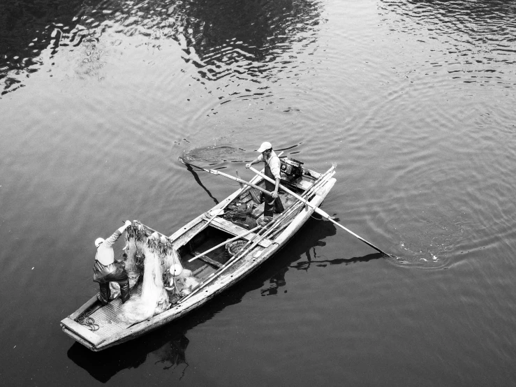 a black and white photo of a man in a boat, by Patrick Pietropoli, flickr, shin hanga, 3 boat in river, repairing the other one, taking from above, fishing