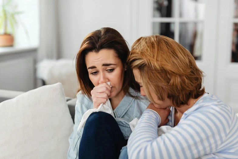 a couple of women sitting on top of a couch, a photo, trending on pexels, crying one single tear, manuka, nursing, mourning family