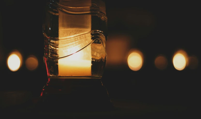 a jar filled with a lit candle sitting on top of a table, inspired by Elsa Bleda, pexels contest winner, yellow light, it's late at night, lantern, light water
