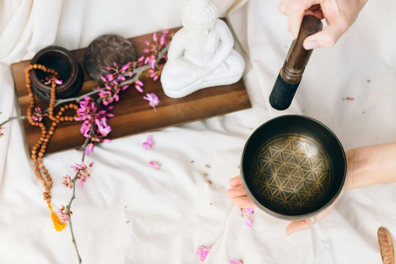 a person holding a bowl with a flower of life on it, an album cover, trending on pexels, tea ceremony scene, wind chimes, bed of flowers on floor, mandalas