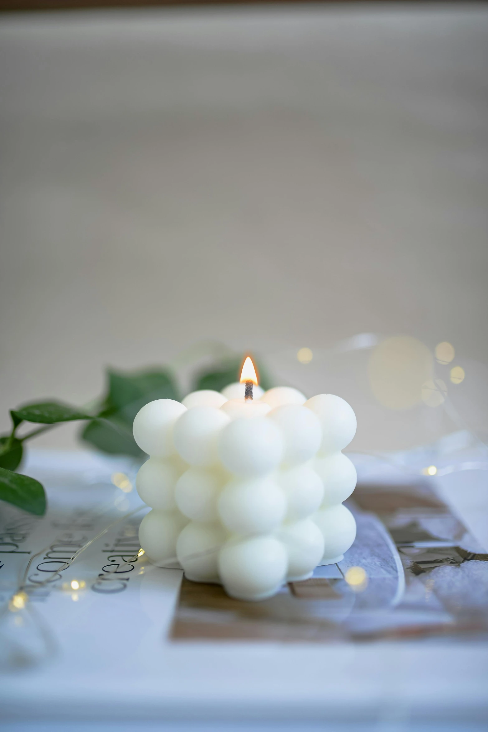 a white candle sitting on top of a table, a marble sculpture, floating bubbles, borg cube, cosy, clover