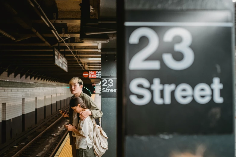 a couple of people standing on a train platform, by Carey Morris, unsplash contest winner, mta subway entrance, street signs, she is 2 3, thumbnail