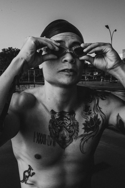 a black and white photo of a man with tattoos on his chest, inspired by Randy Vargas, pexels contest winner, next to a pool, wearing an eyepatch, set on singaporean aesthetic, yung lean