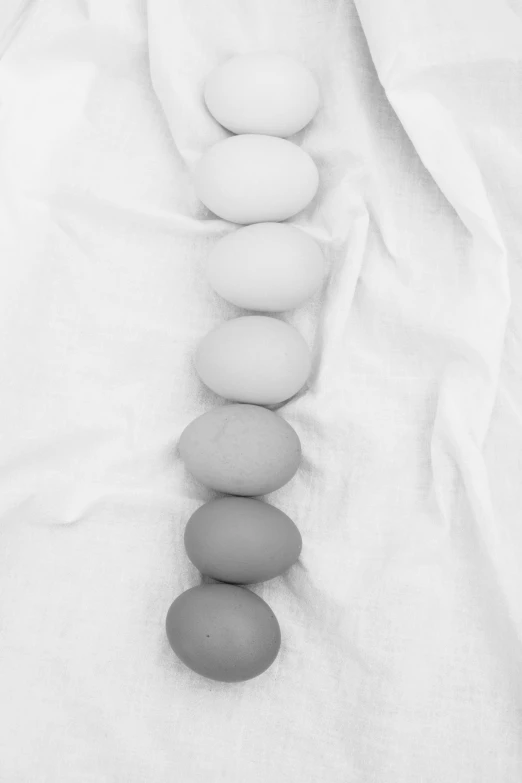 a close up of a person wearing a white shirt, a black and white photo, inspired by Robert Mapplethorpe, unsplash, eggs, pastel faded grey rainbow, in a row, ffffound