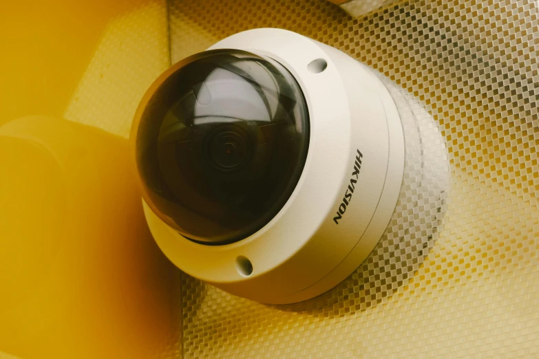 a close up of a camera on a wall, high angle security camera feed, nathan fowkes, futuristic yellow lens, high quality product image”