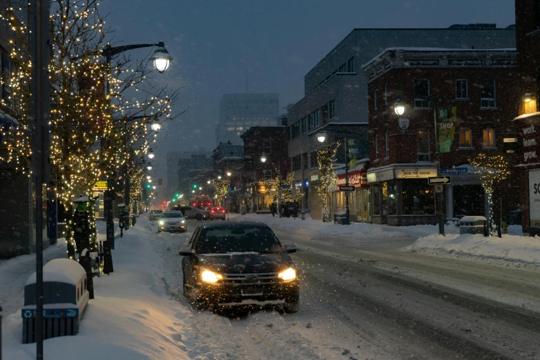 a car driving down a snow covered street, by Carey Morris, pexels contest winner, warm street lights store front, square, quebec, grey