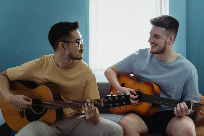 two men sitting on a couch playing guitars, inspired by Wang Duo, pexels contest winner, avatar image, college students, lgbt, background image