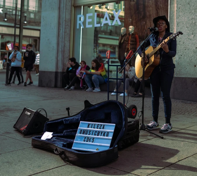 a woman standing next to a guitar on a sidewalk, by Gina Pellón, pexels contest winner, protest movement, on a sidewalk of vancouver, performing on stage, a labeled