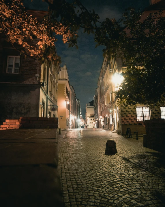 a person walking down a cobblestone street at night, by Adam Marczyński, happening, warsaw, cover image, high quality upload, multiple stories
