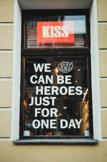a window with a sign that says we can be heroes just for one day, a poster, pexels contest winner, the kiss, shop front, super strong, i_5589.jpeg