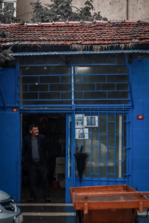 a man standing in front of a blue building, istanbul, office/thrift store/social hall, 2019 trending photo, ap news photo