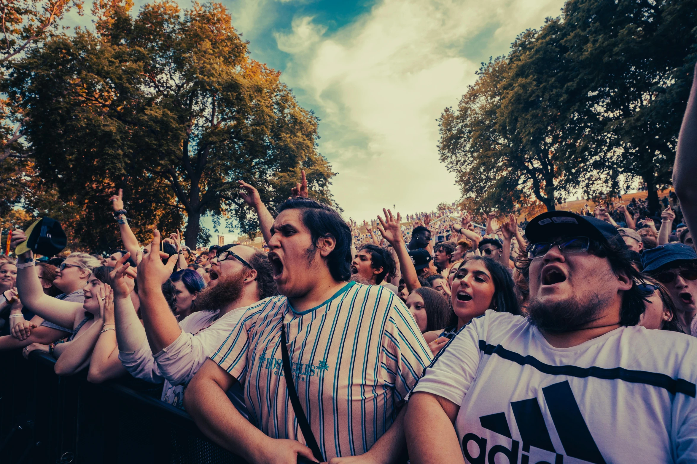 a crowd of people with their hands in the air, an album cover, by Lee Loughridge, pexels contest winner, happening, smug look, full trees, vapourwave, where's wally