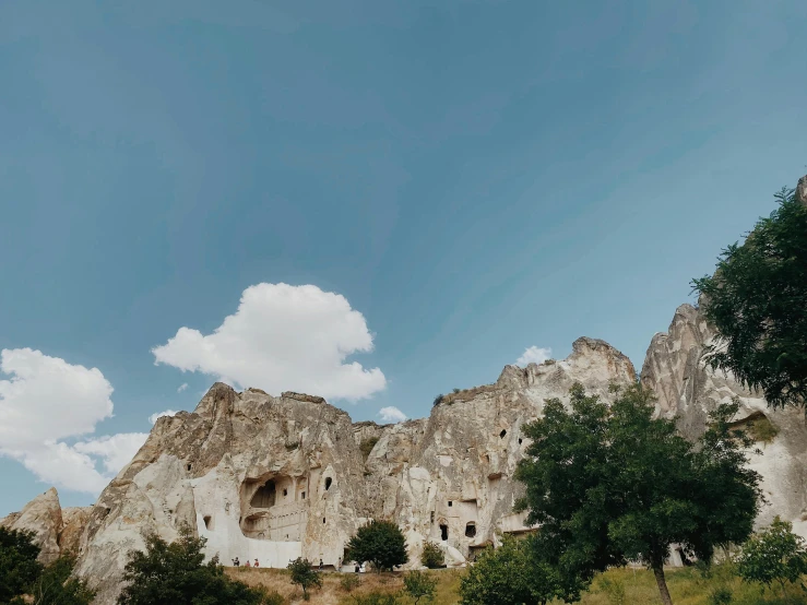 a group of trees sitting on top of a lush green hillside, by Muggur, pexels contest winner, baroque, cozy bathhouse hidden in a cave, ancient city of white stone, youtube thumbnail, background image