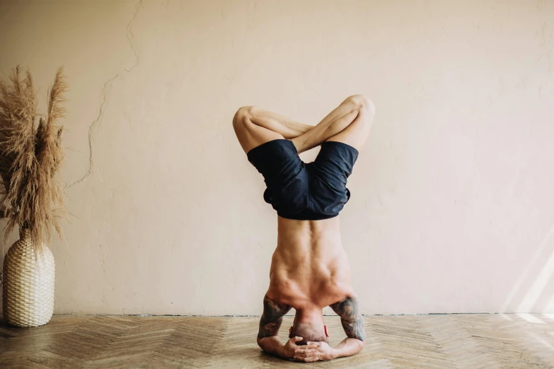 a man doing a handstand on a hard wood floor, trending on pexels, arabesque, background image, lotus pose, australian, shirtless