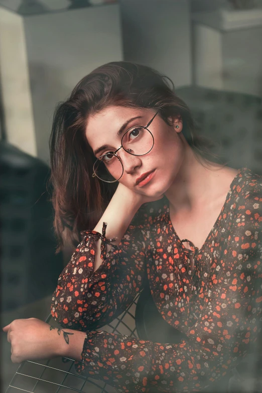 a woman sitting in front of a laptop computer, a colorized photo, inspired by Elsa Bleda, trending on pexels, photorealism, square rimmed glasses, beautiful iranian woman, girl with brown hair, casual pose