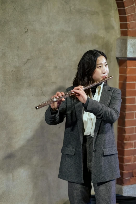 a woman in a suit playing a flute, inspired by Gu Kaizhi, unsplash, photorealism, performance, underground scene, production photo, small