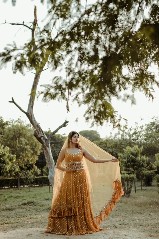 a woman in a yellow dress standing under a tree, indian super model, bride, instagram photo, brown